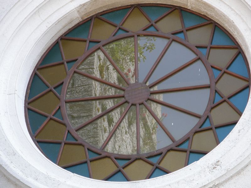 Glockenturm spiegelt sich im Kirchenfenster